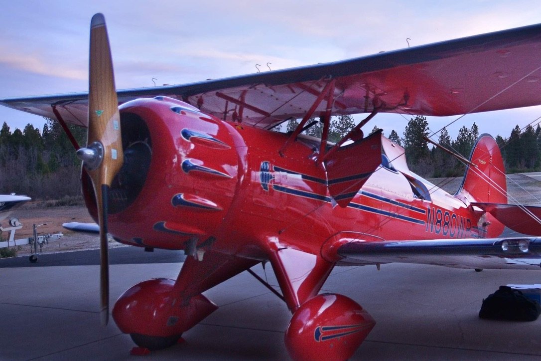 Red Waco biplane at dusk with a wooden MT propeller