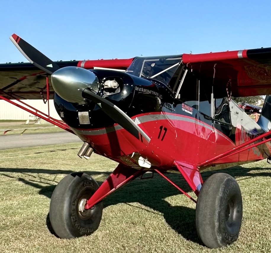 Red and black Aviat Husky number 17 with a black MT propeller on grass