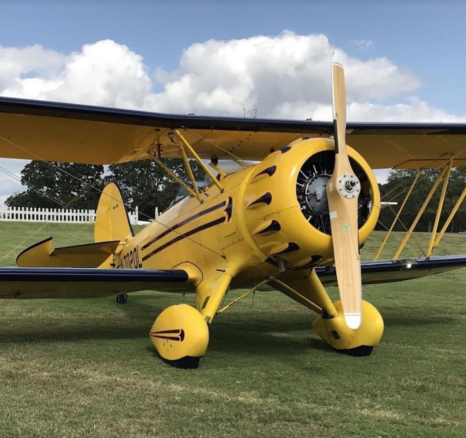 Yellow Waco biplane on grass with a wooden MT propeller