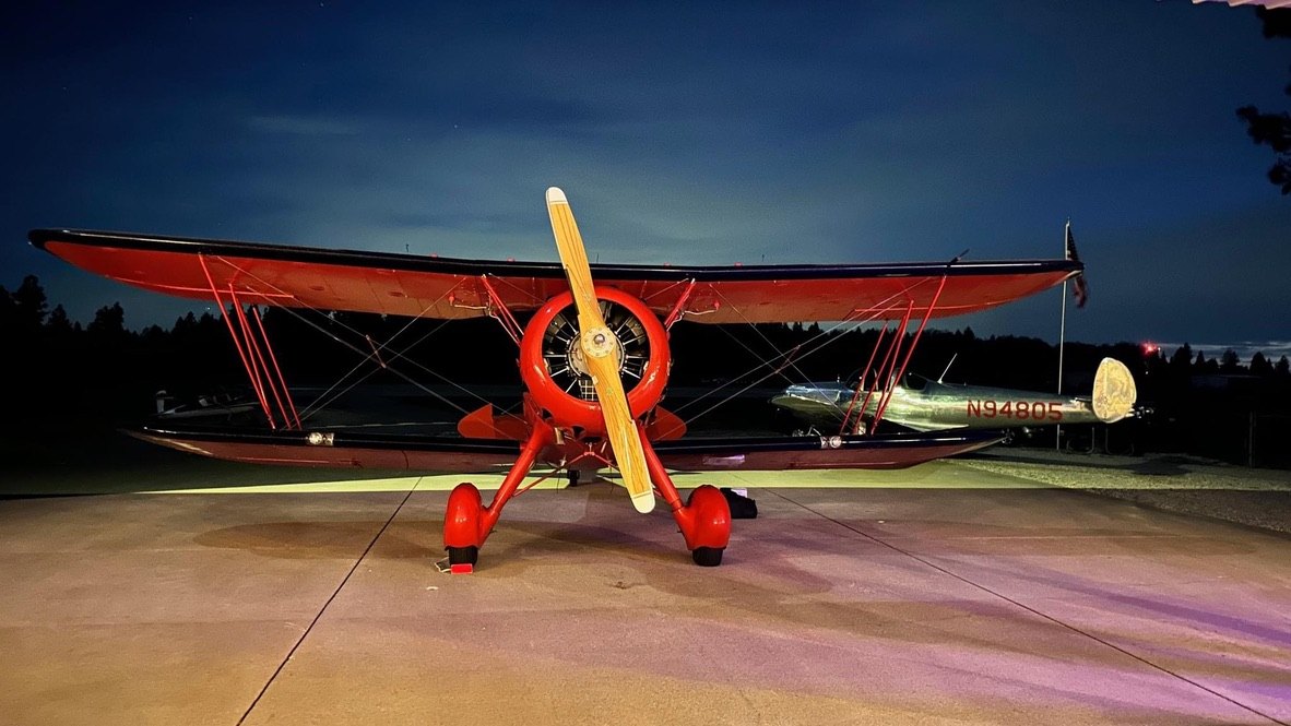 Red Waco biplane at night with a wooden MT propeller