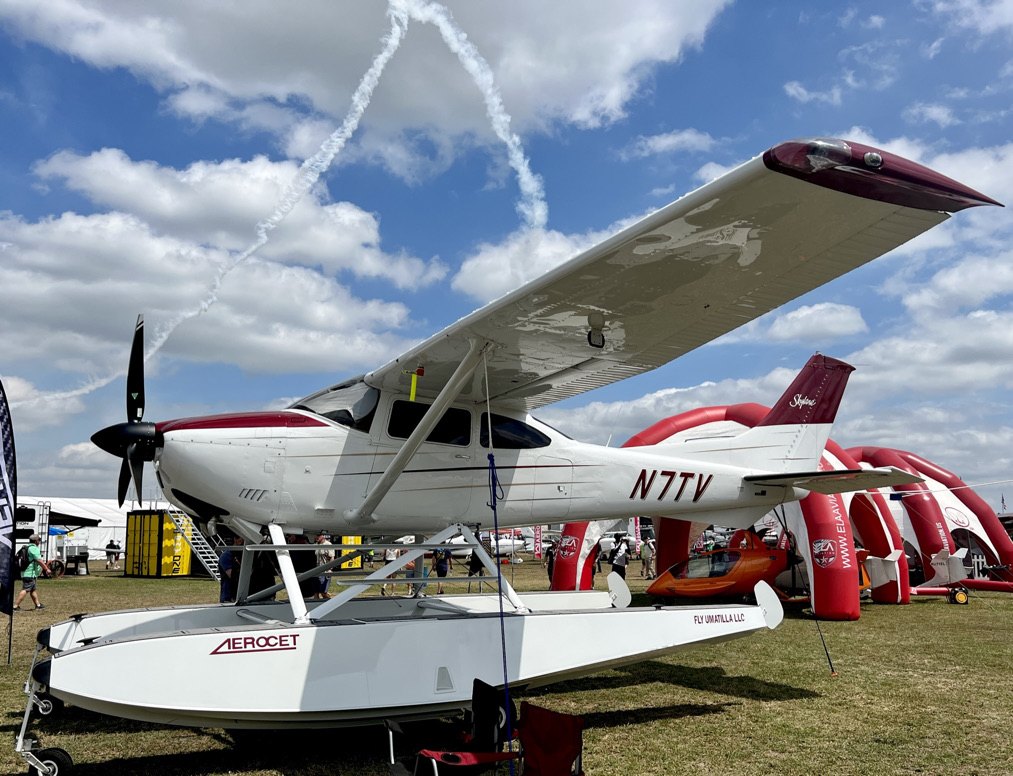 White and maroon floatplane on Aerocet floats with a black MT propeller at an airshow