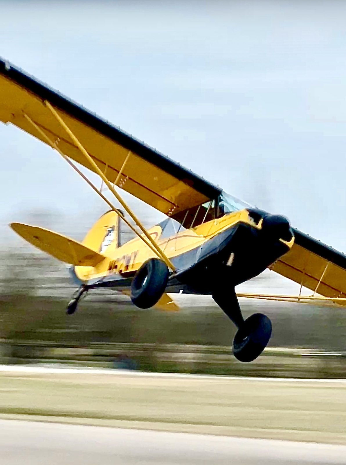 Yellow bush plane banking low with a motion-blurred background
