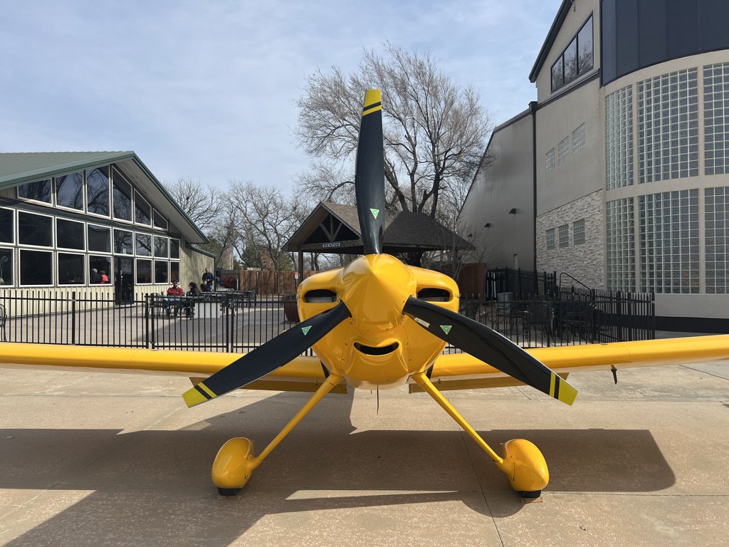 Yellow race plane head-on with a black two-blade MT propeller