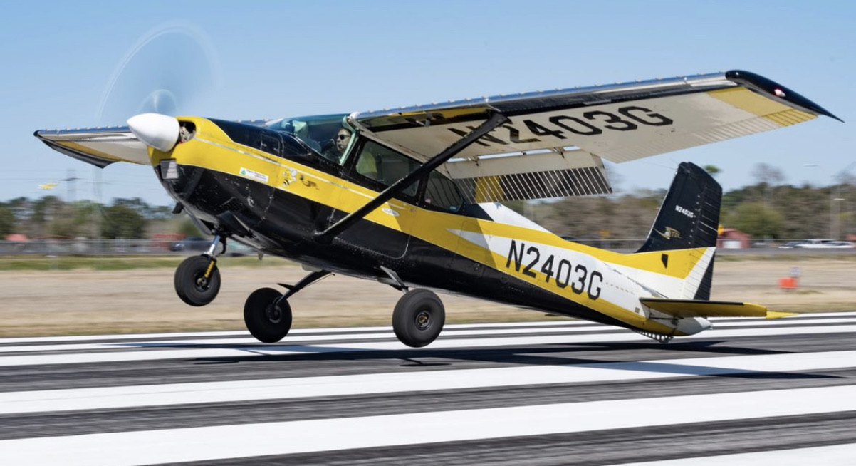Yellow and black Cessna 180 N2403G landing on a striped runway