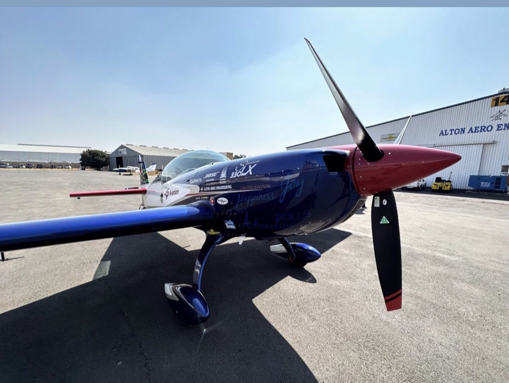 Blue Extra 330LX aerobatic aircraft with a red spinner and black MT propeller on the ramp