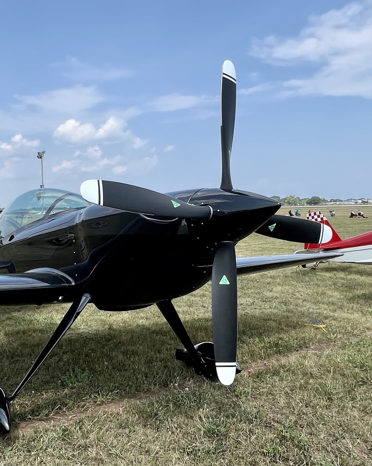 Black aerobatic aircraft on grass with a black three-blade MT propeller