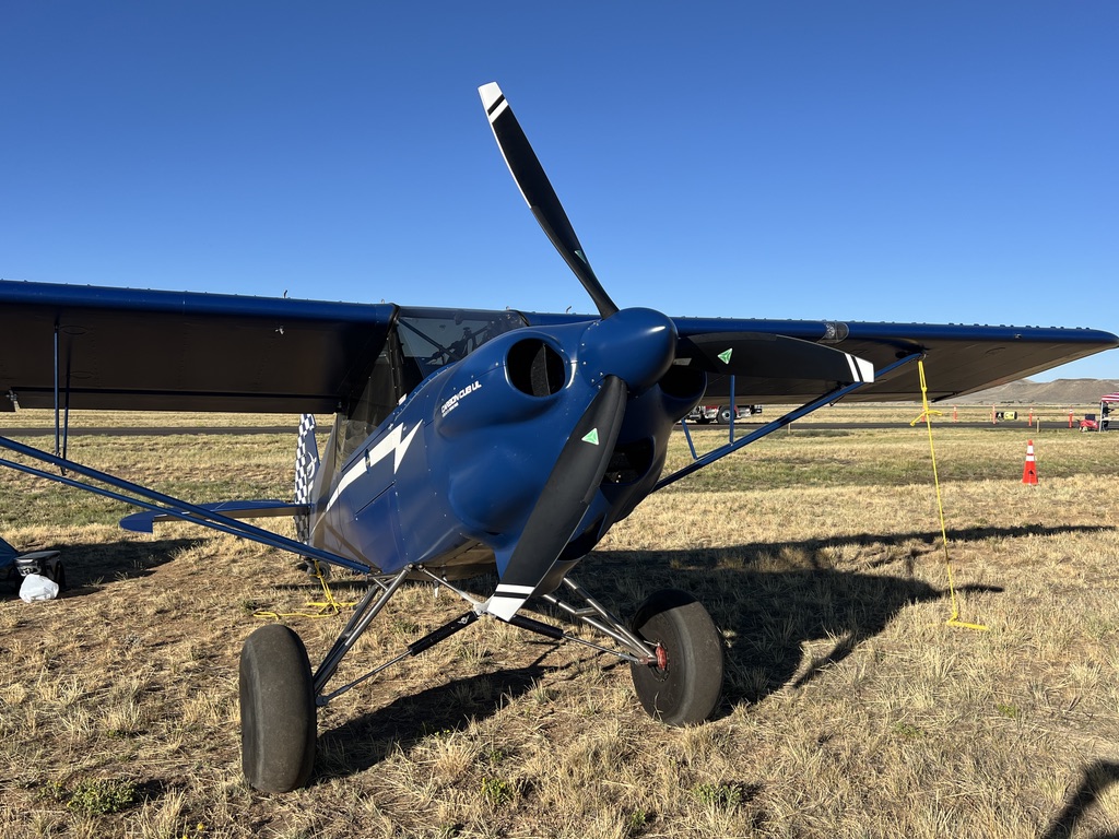 Blue Carbon Cub UL with a black two-blade MT propeller parked on dry grass under a clear blue sky