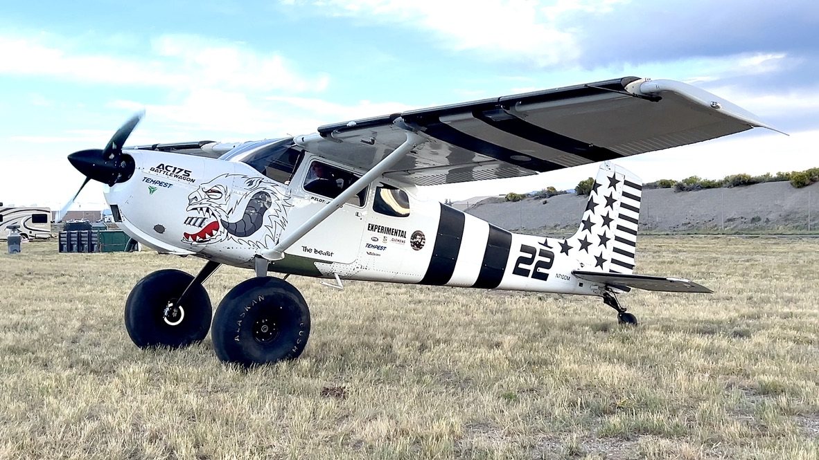 White Cessna 175 bush plane number 22 with large tires, a black MT propeller and a shark mouth on the cowling