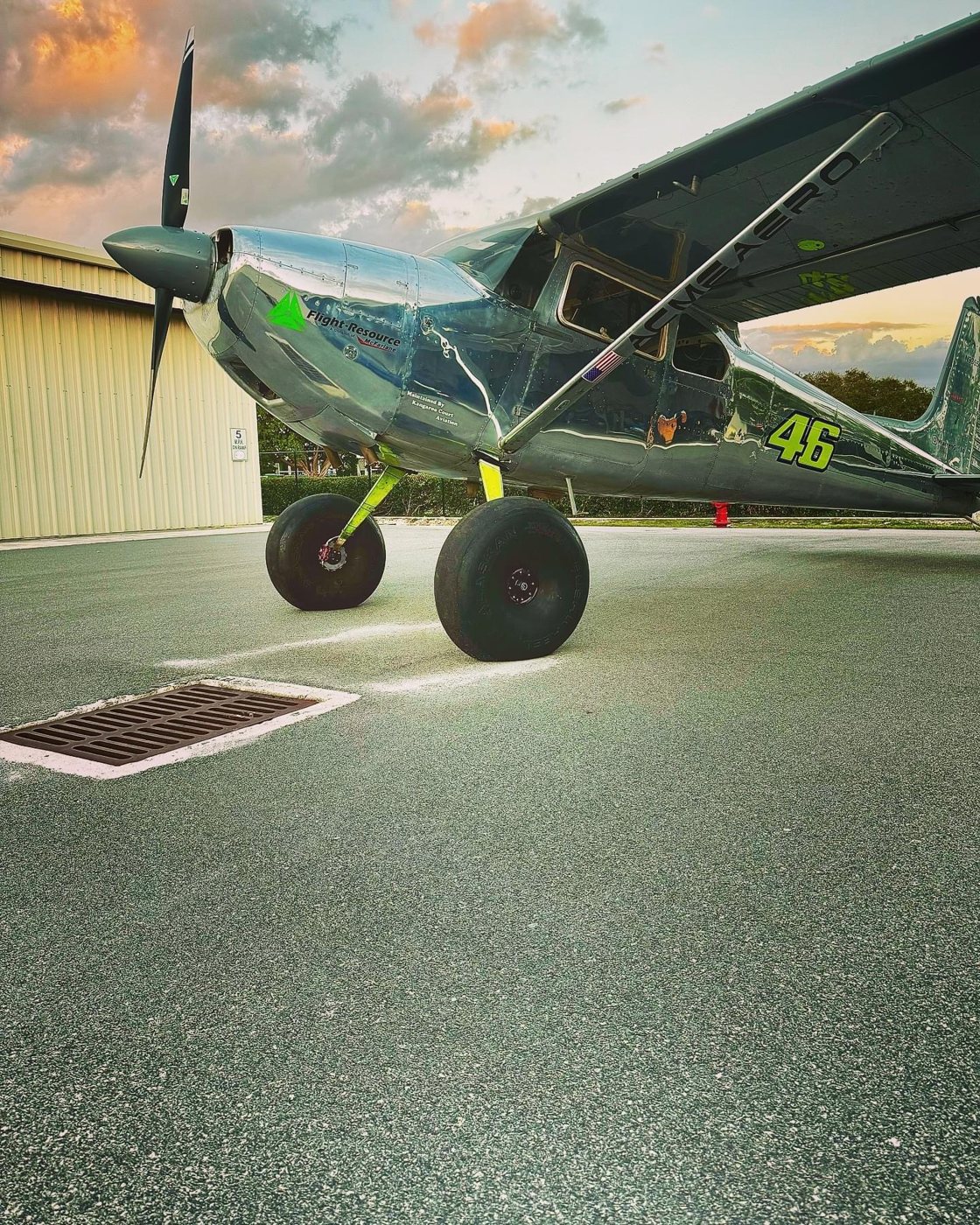 Polished aluminum Cessna with a black MT propeller and a Flight-Resource logo, parked at sunset